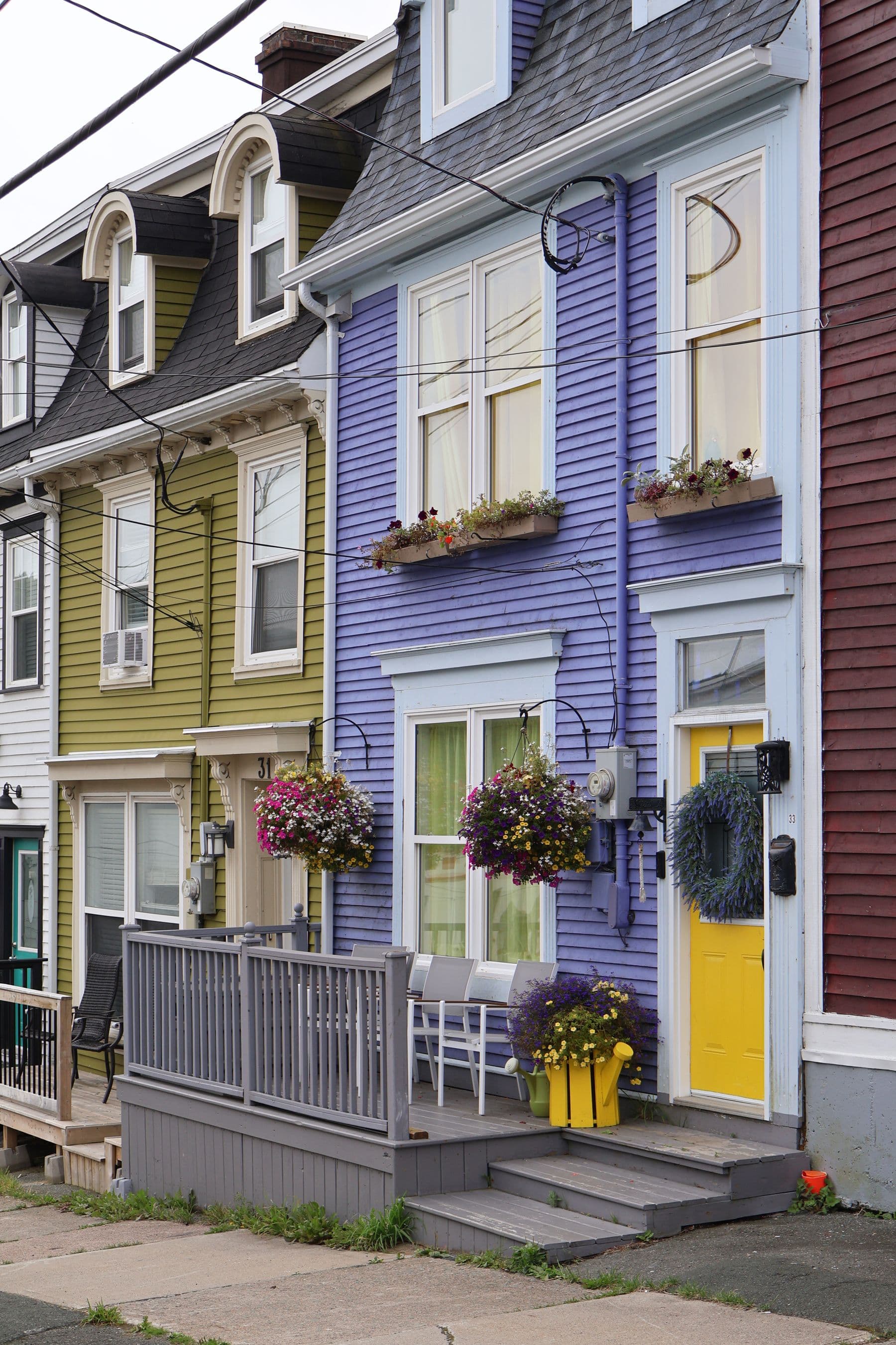 A row of painted clapboard houses with flower boxes and front steps on a street in St. John's, Newfoundland.